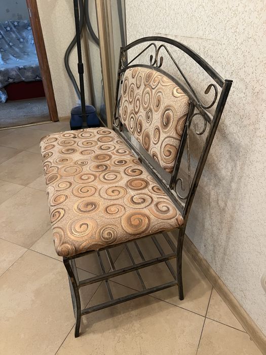 Кована банкетка з мʼяким сидінням і спинкою та металева підставка.