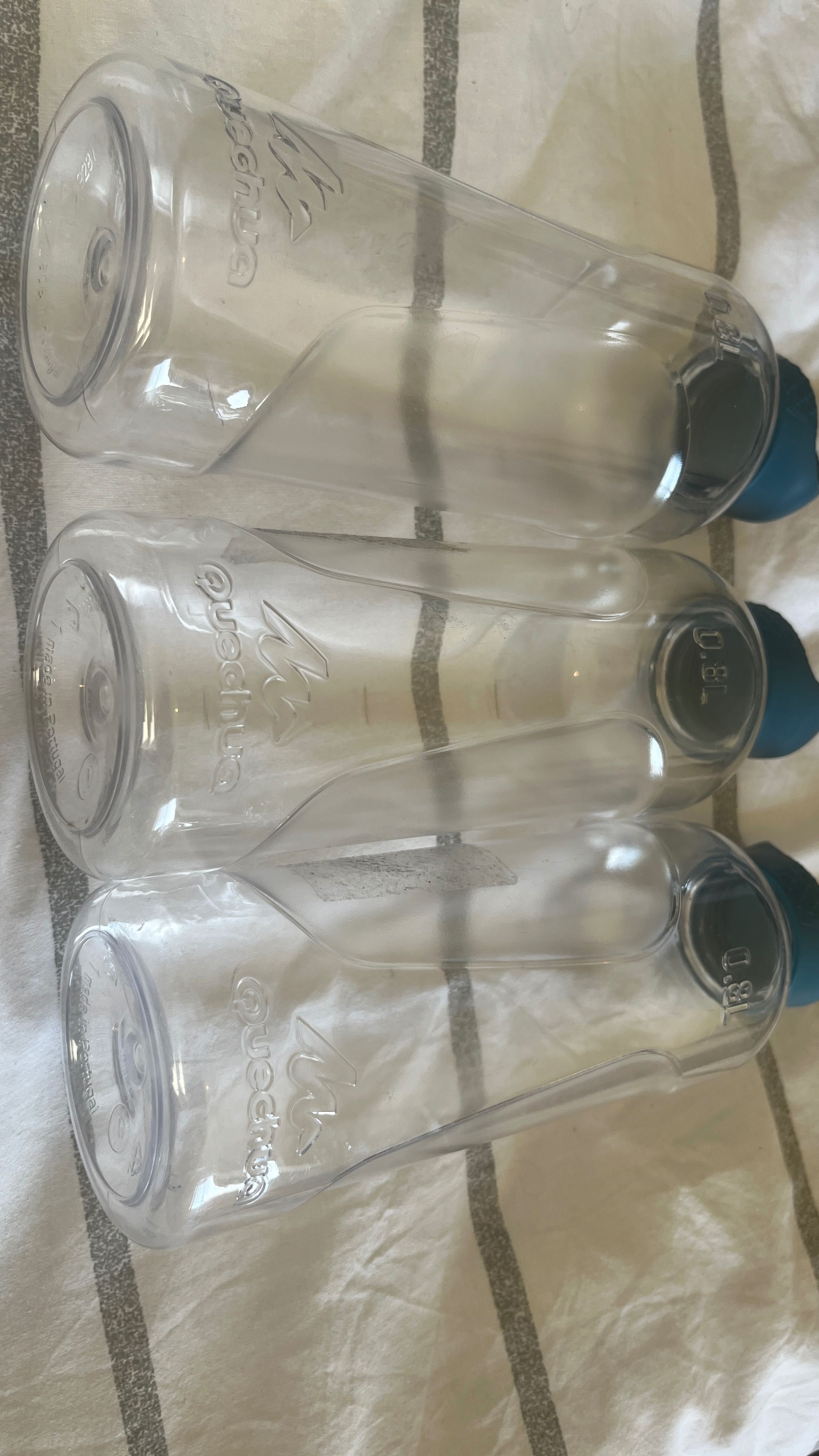 Três garrafas de plástico transparentes, todas com tampa azul.