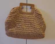 Bolsa de palha trançada com alça de mão.