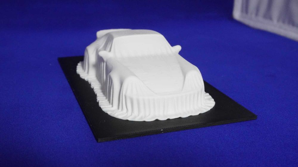 3D-фігурка Porsche 911 Turbo під покривалом на п’єдесталі