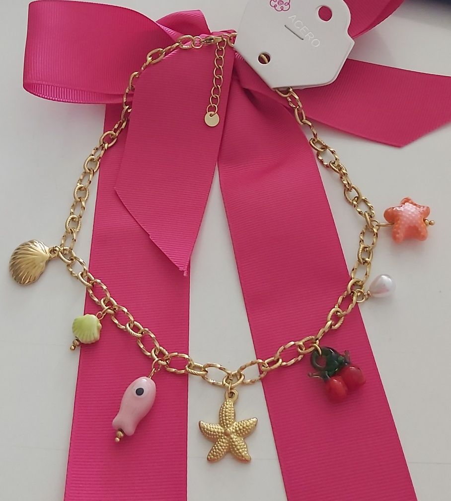 Colar dourado, em aço, com 7 pingentes diferentes. Tem extensor