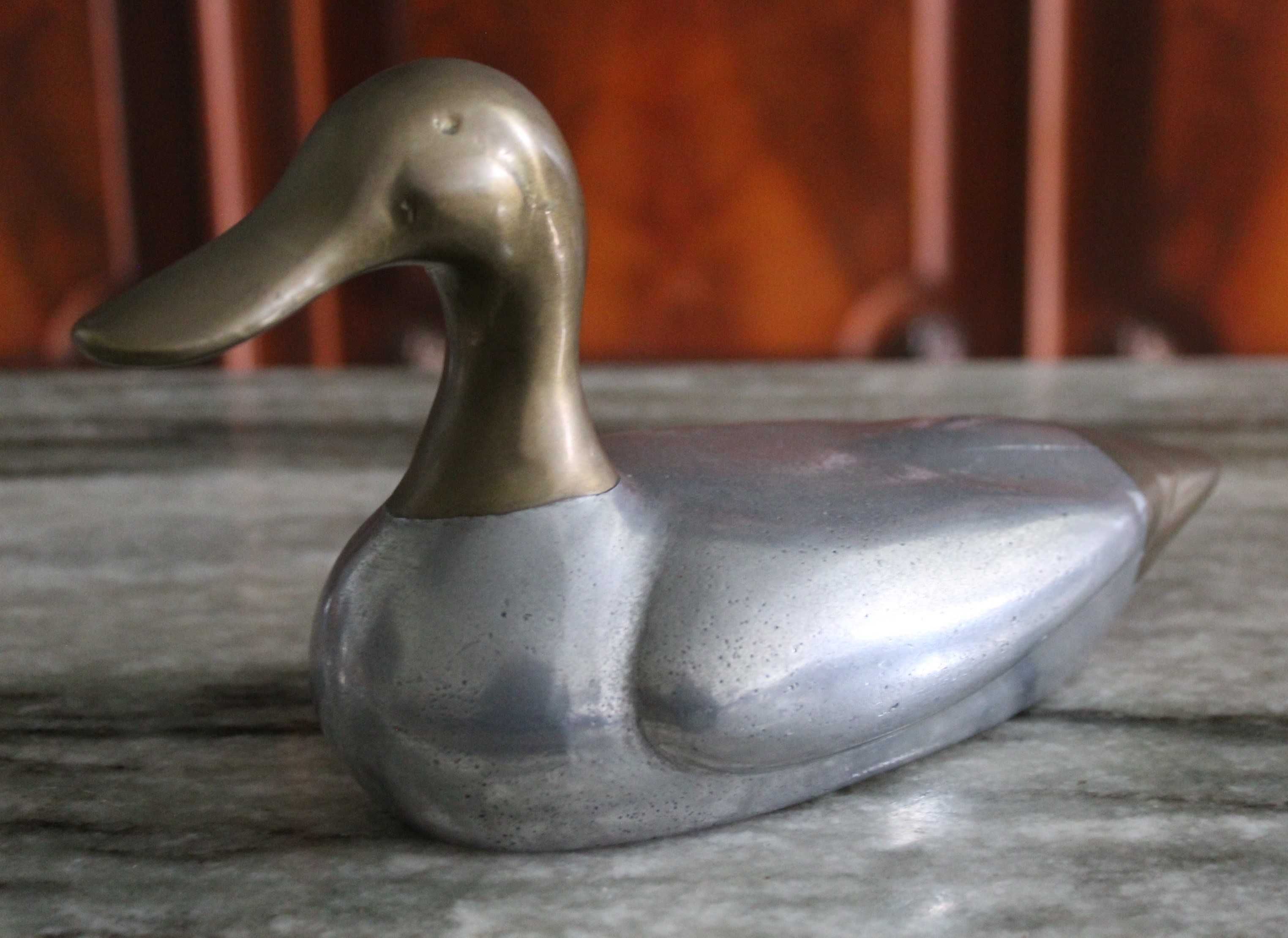 Estatueta vintage de pato, corpo prateado e a cabeça e cauda douradas.