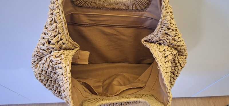 Bolsa de palha trançada com alça de mão.