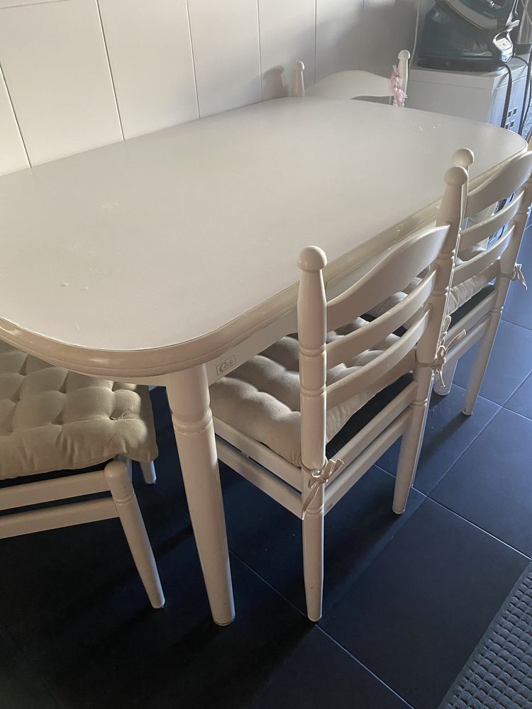Mesa com 4 cadeiras e um banco lacada de branco com cuchins