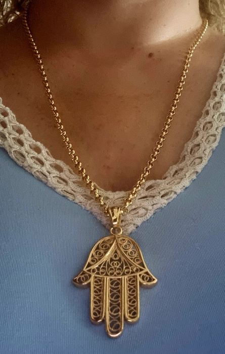 Colar comprido dourado, em aço, com a mão de Fátima em filigrana..
