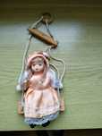 Mała porcelanowa laleczka na huśtawce
