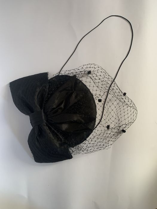 Чорний капелюшок-таблетка з вуаллю та бантом.