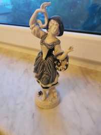 Porcelanowa figurka kobiety z koszyczkiem.