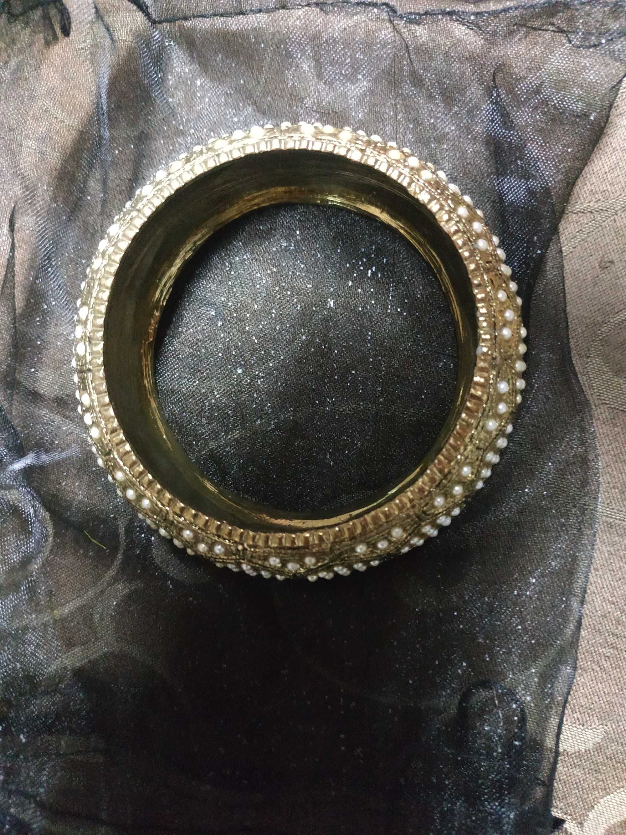 Uma pulseira dourada crivada de pérolas.