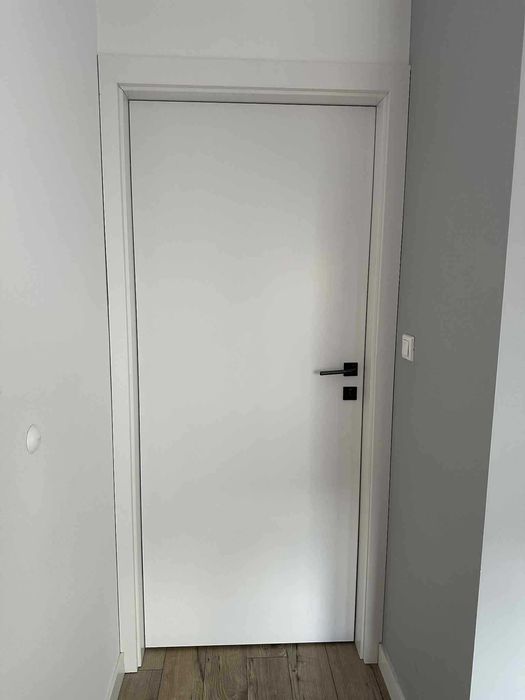 Białe drzwi wewnętrzne z oscieżnicą i klamką