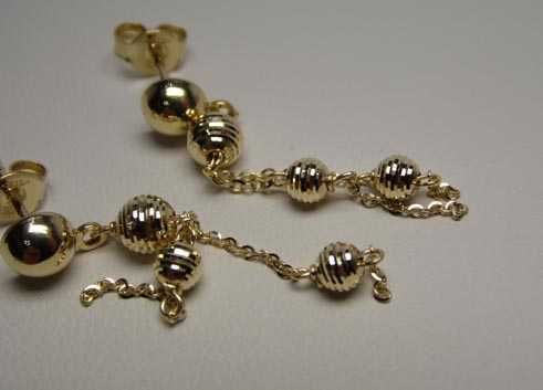 Złote wiszące kolczyki łańcuszki i diamentowane kulki.