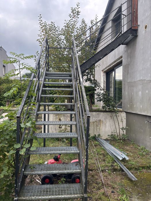 Metalowe schody zewnętrzne z kratownicy stopnie, podest i konstrukcja.