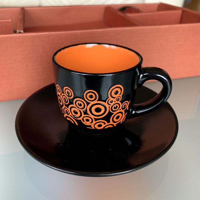 Caixa com quatro chávenas de café coloridas e pires.