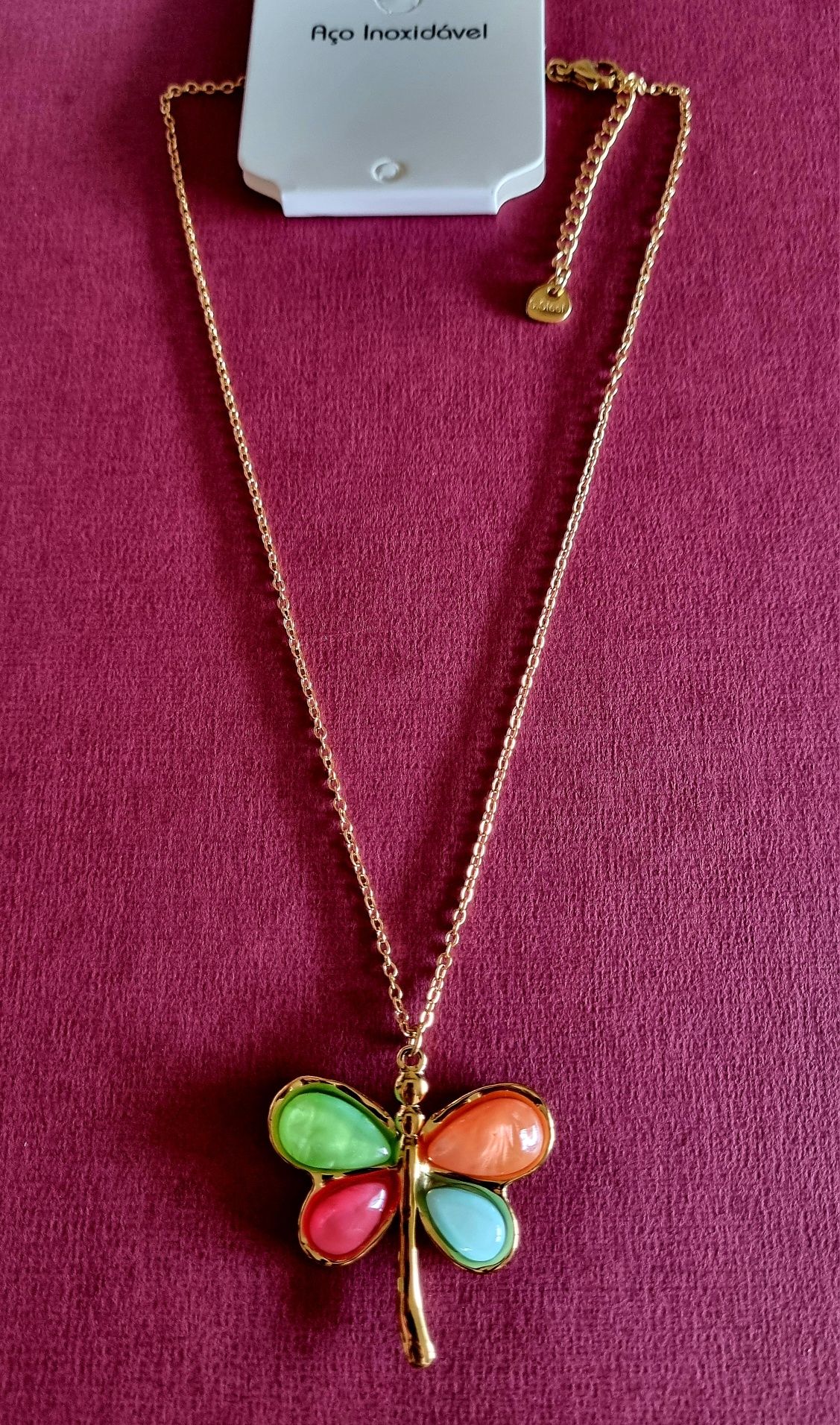 Colar dourado, em aço, com libelinha colorida. Tem extensor