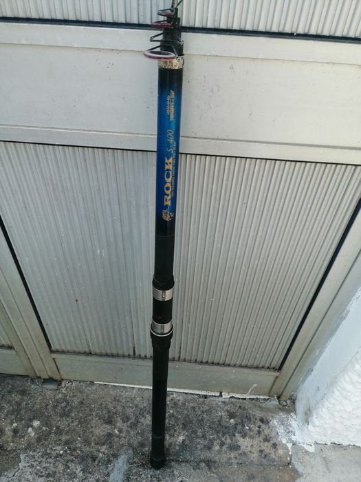 Uma cana de pesca usada pronta a usar e um carreto estão adicional