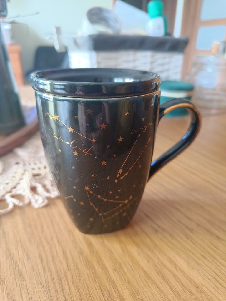 Kubek czarny że złotym znak zodiaku