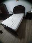 Cama de casal de madeira maciça com colchão de 140cm por 190cm.