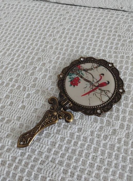 Lusterko z metalowej oprawie.