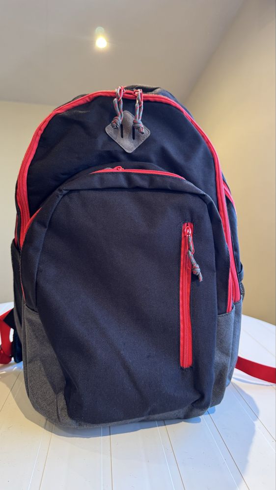 Mochila preta com os fechos em vermelho