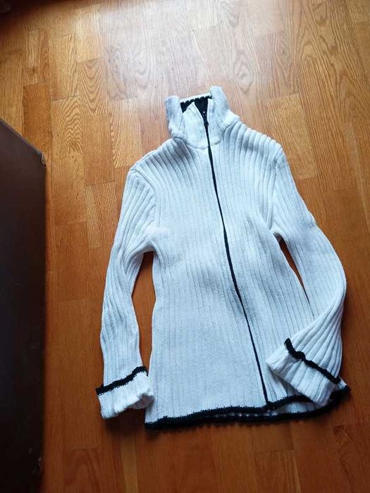 Sweter biały zapinany na zamek z ciemnymi lamówkami.