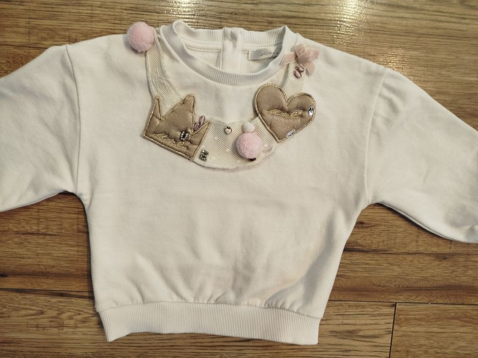 Biała bluza bawełna 80 86 z ozdobną odpinaną dekoracja na dekolcie.