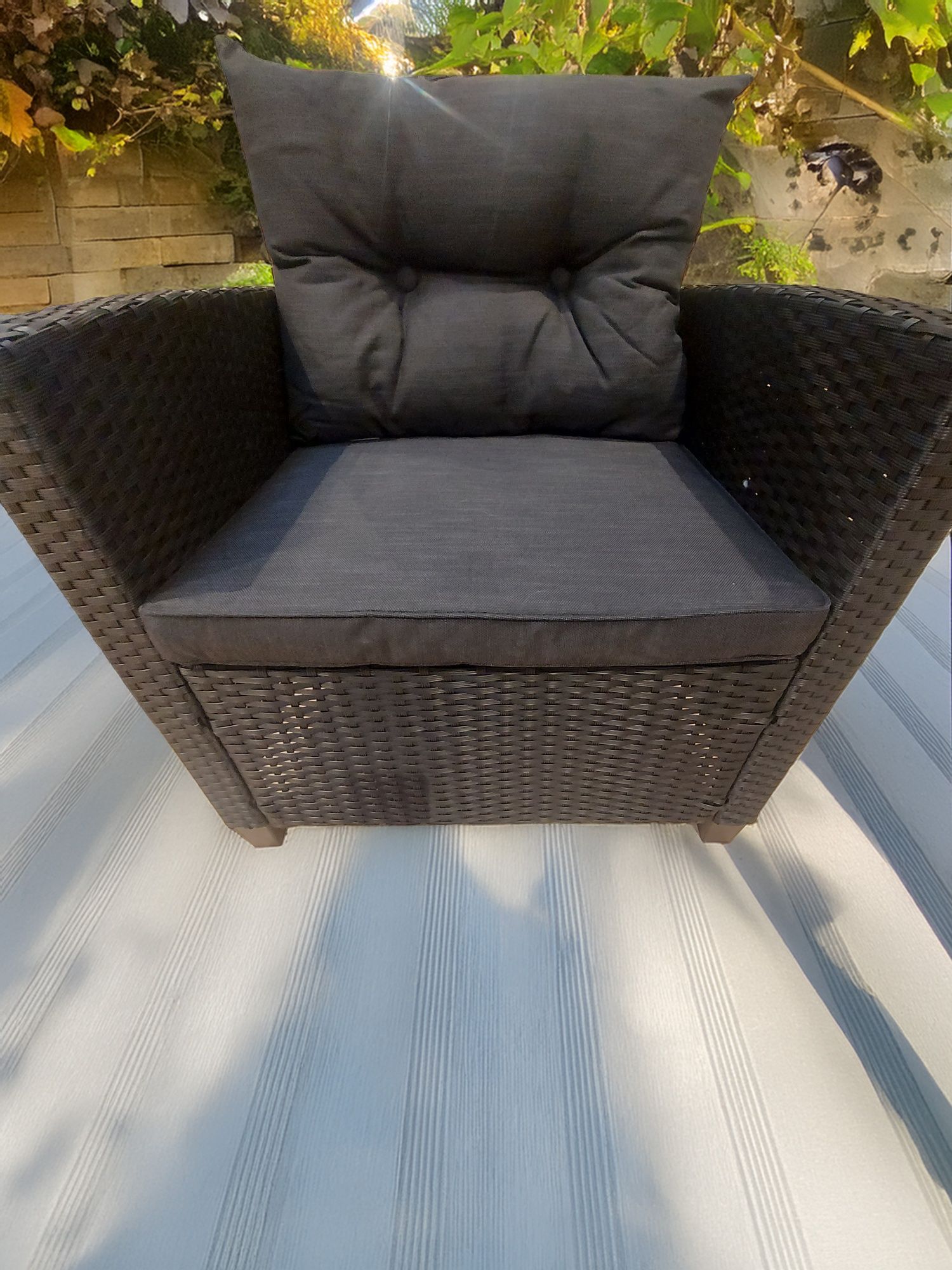 Meble ogrodowe sofa plus dwa fotele i stolik z drewnianym blatem.