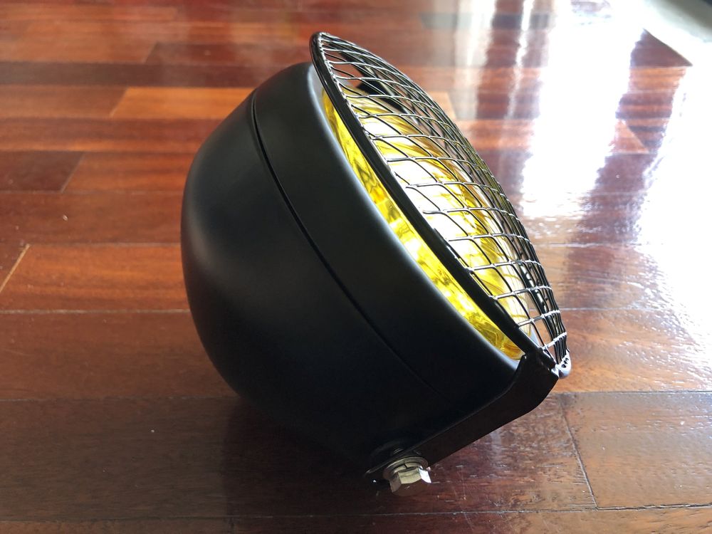 Farol frontal amarelo com grelha metálica dois apoios cafe racer