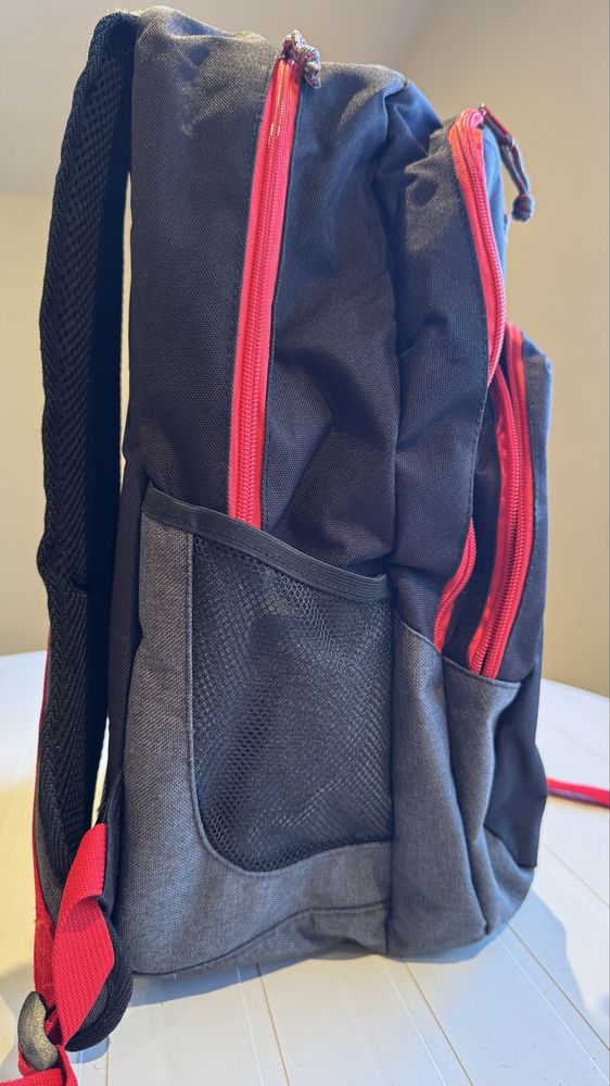 Mochila preta com os fechos em vermelho