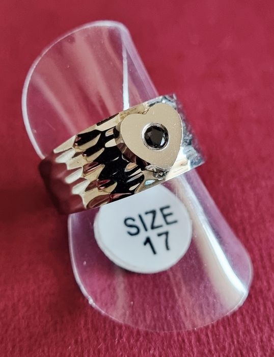 Anel prateado, em aço, com 1 coração com pedrinha preta no centro. T17