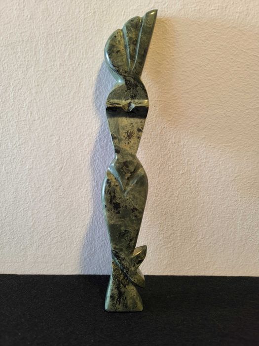 Escultura de mulher em pedra de cor verde.