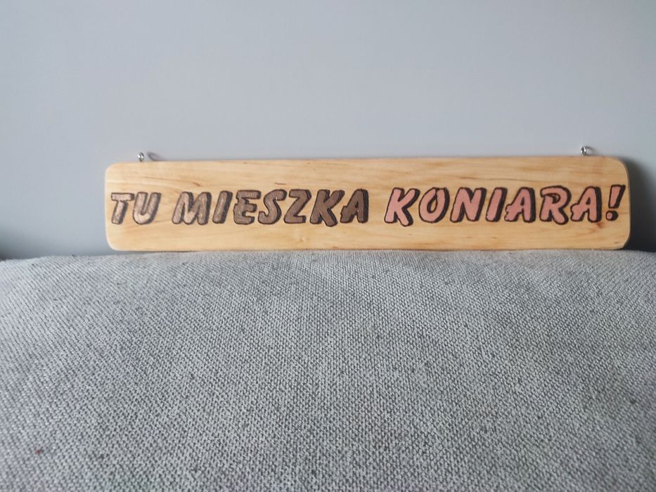 Drewniana tabliczka zawieszana z napisem: Tu mieszka koniata!