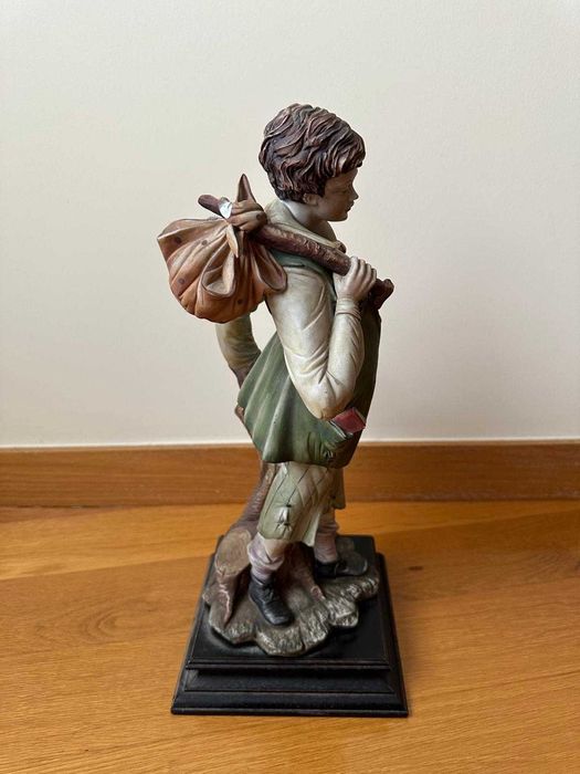 Estatueta de menino com saco ao ombro