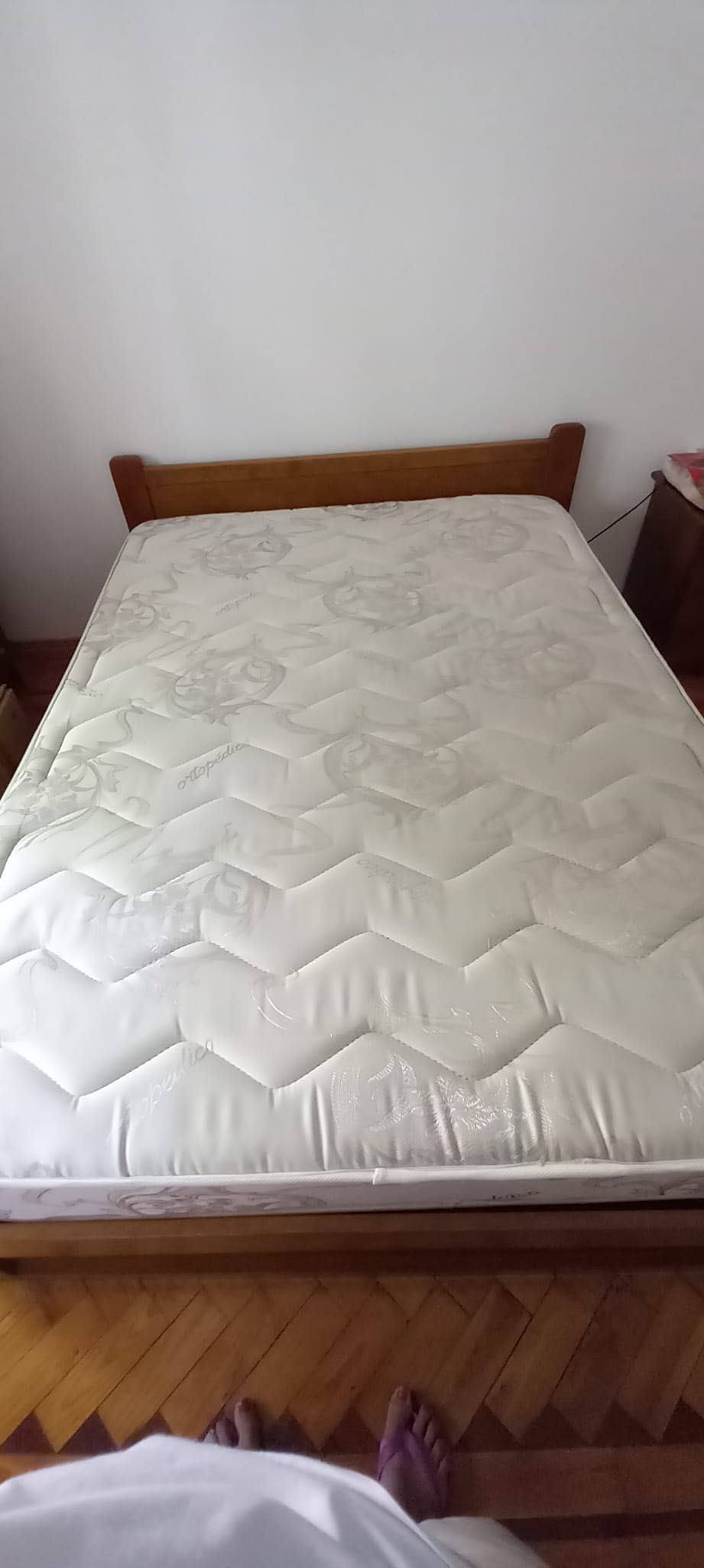 Cama de casal de madeira com colchão e mesa de cabeceira