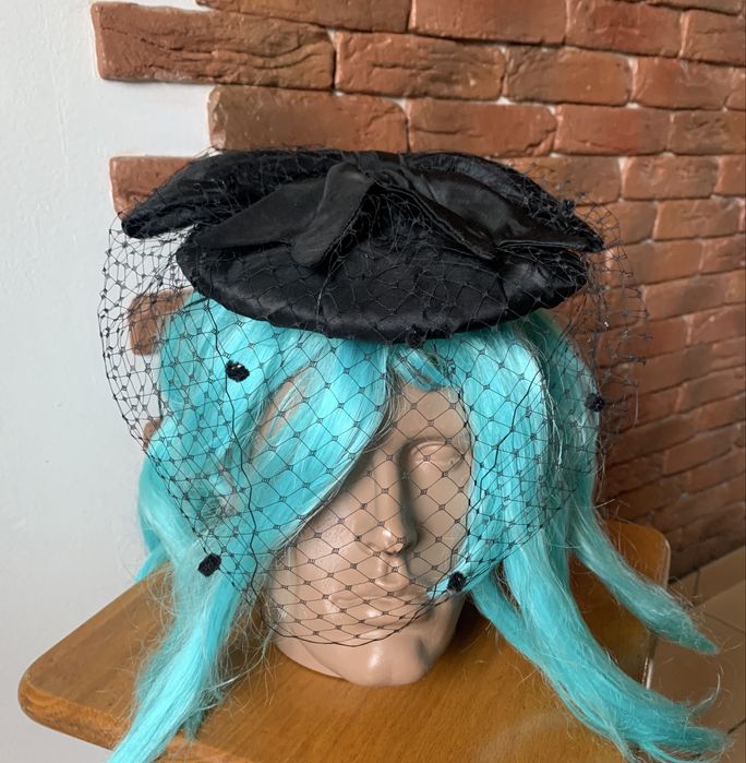 Чорний капелюшок-таблетка з вуаллю та бантом.