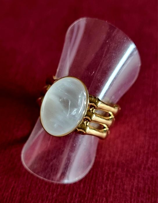 Anel dourado, em aço, com uma madrepérola oval.  Ajustável