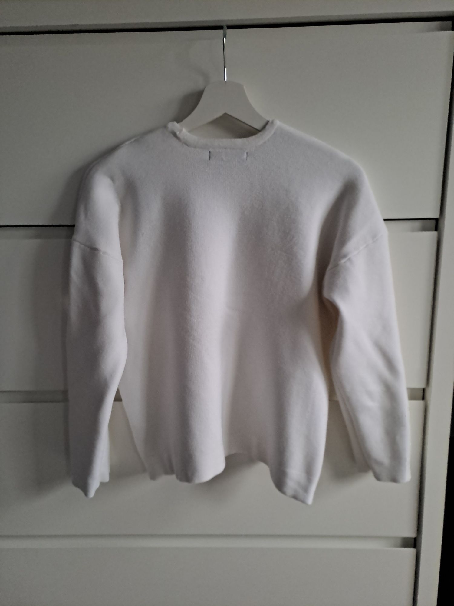 Bialy sweter z modna aplikacja