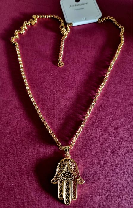 Colar comprido dourado, em aço, com a mão de Fátima em filigrana..