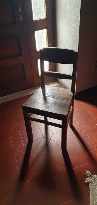 Cadeira antiga em madeira maciça, resistente e estável.