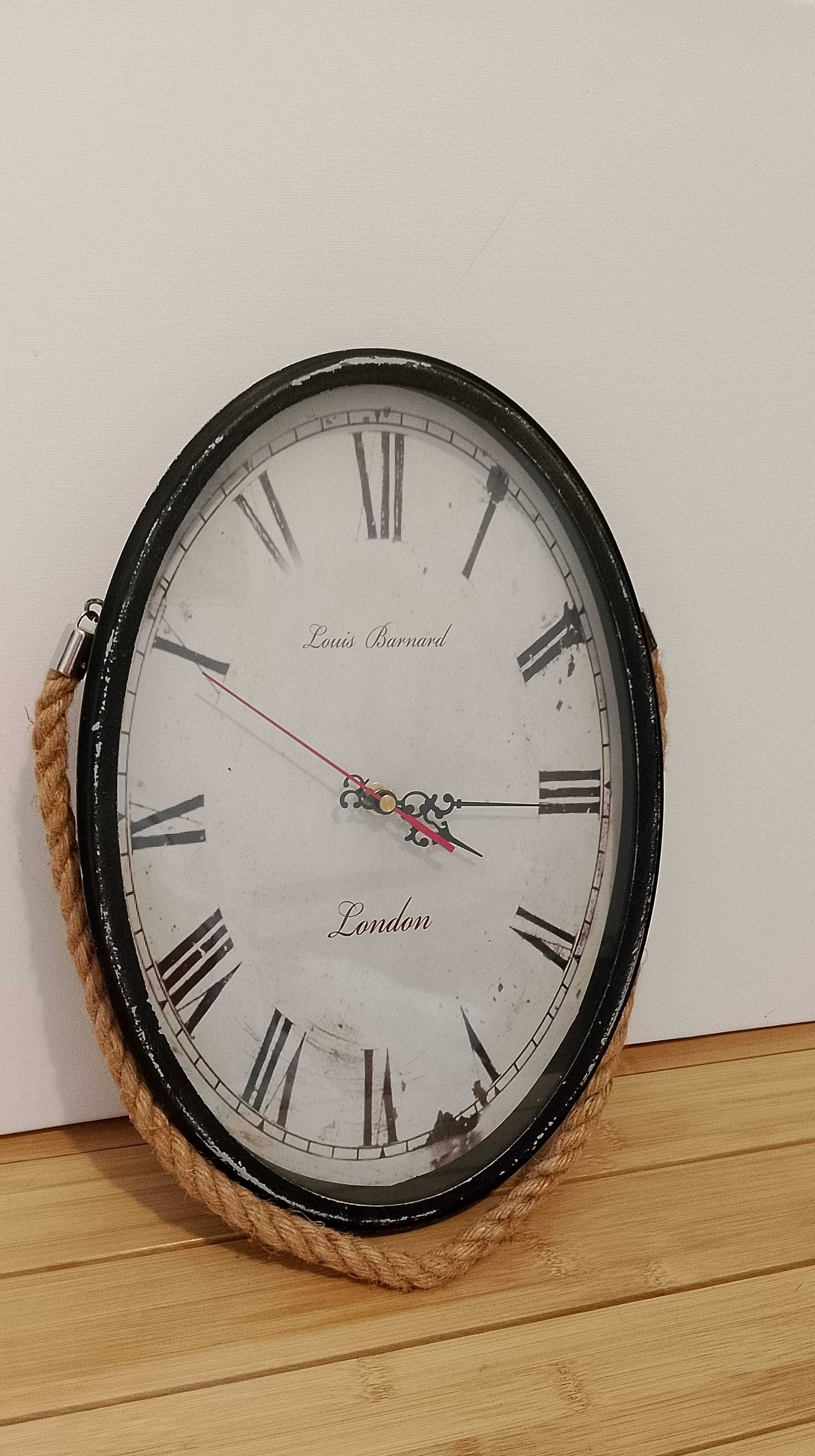 Duży zegar ścienny, wiszący na sznurze, styl vintage.