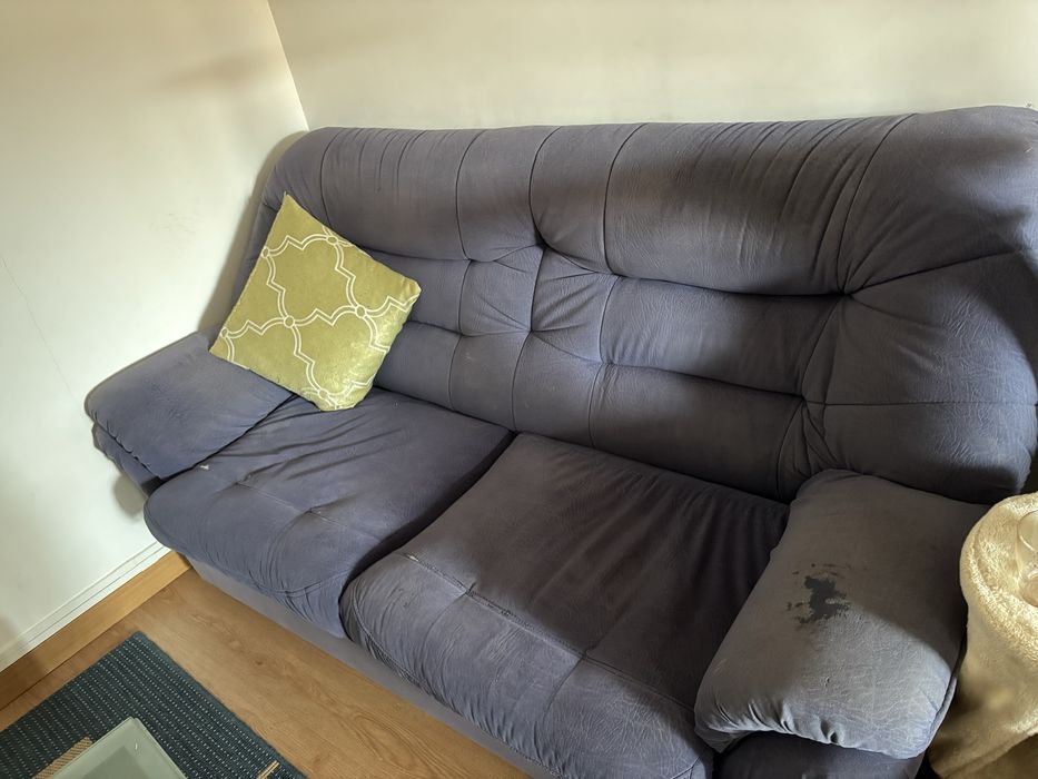 Sofá de sala, azul, com alguns anos e marcas de uso.