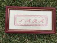 Quadro em ponto cruz com o nome “Lara” a cor-de-rosa