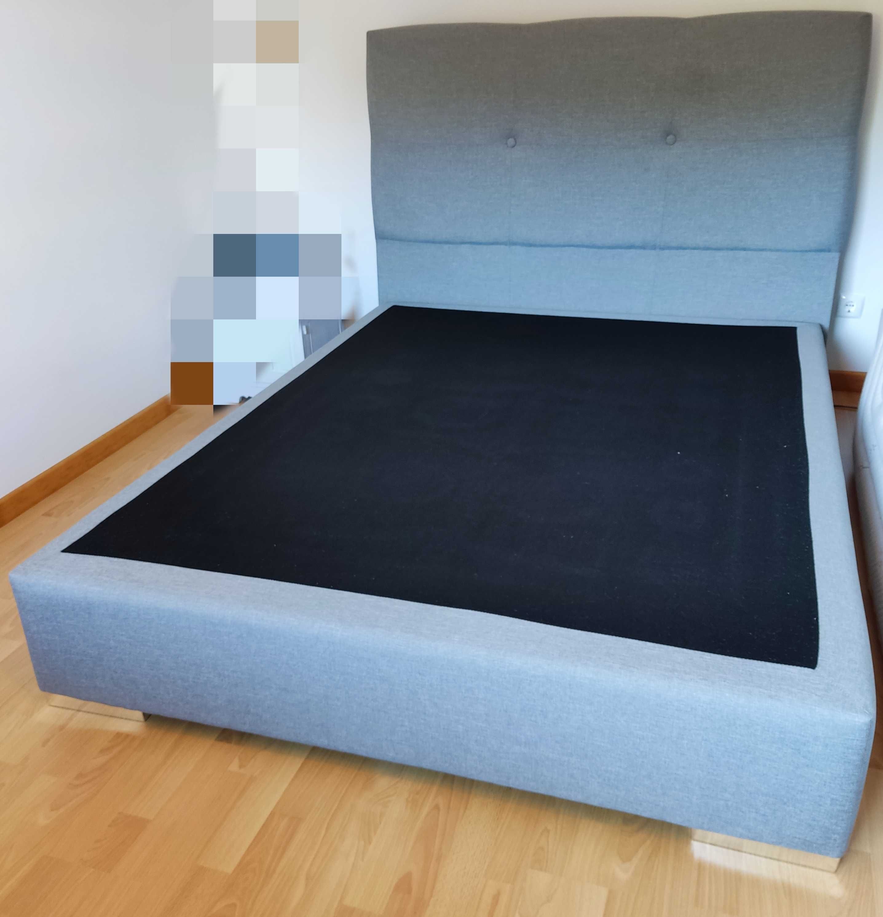 Cama impecável - sem colchão, cor cinza com promenor de pés metálicos.