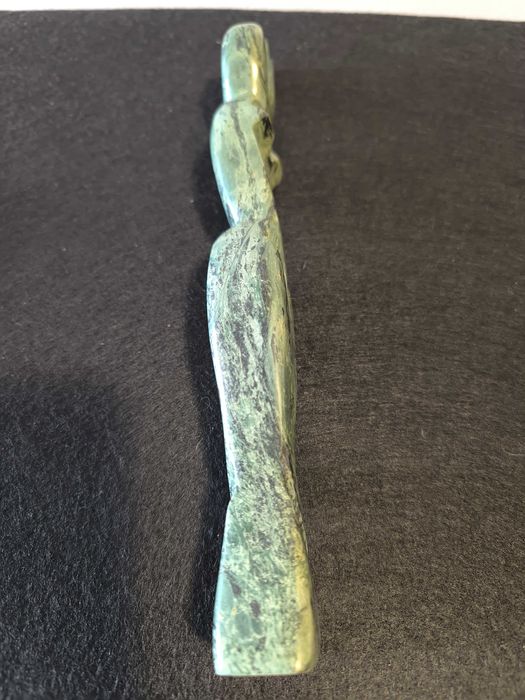 Escultura de mulher em pedra de cor verde.