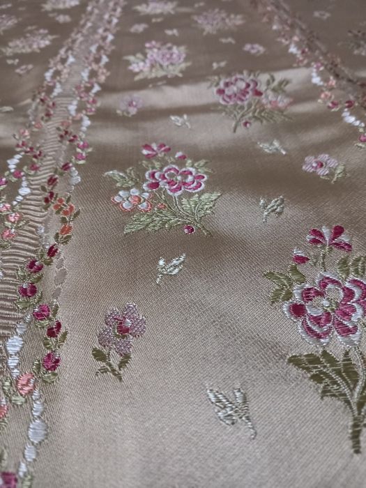 Colcha acetinada antiga com fundo amarelo e bordada com flores.