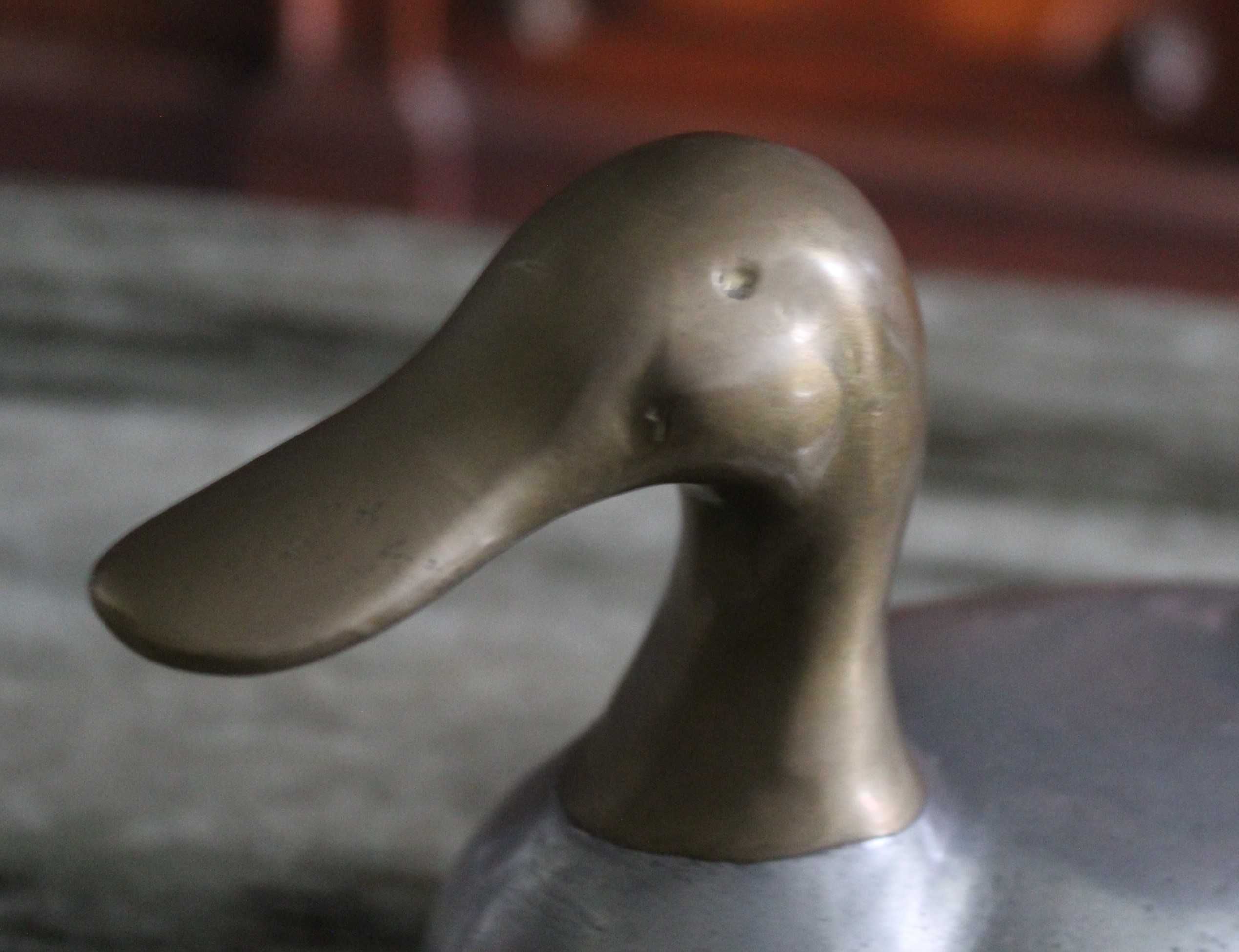 Estatueta vintage de pato, corpo prateado e a cabeça e cauda douradas.