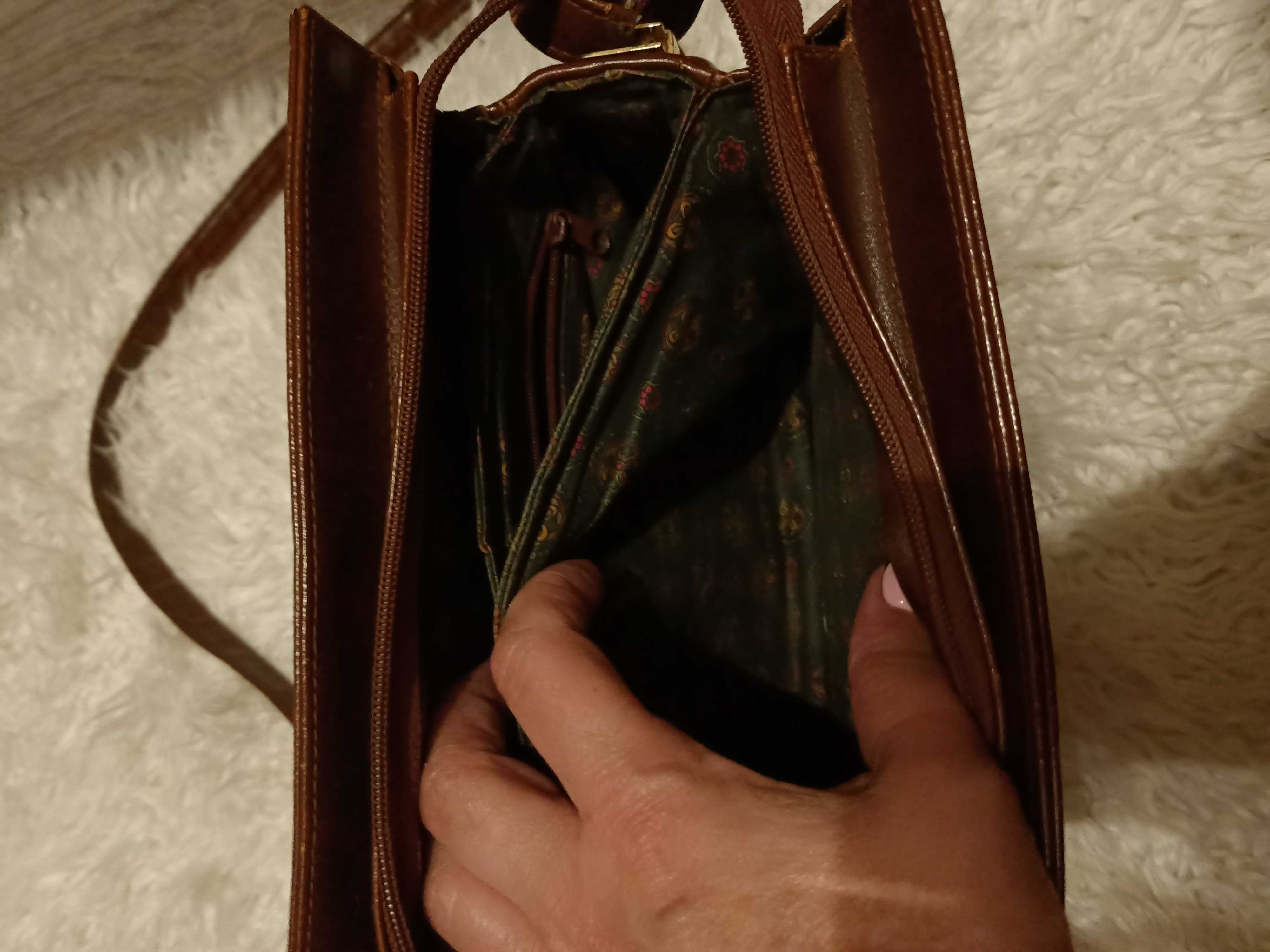 Brązowa torebka na długim pasku, który ma dwie możliwości długości.