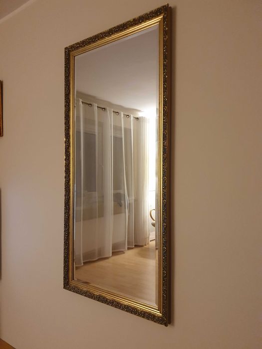 Obrazy i duże lustro z bogato zdobionymi ramami