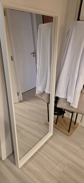 Espelho grande com moldura branca.