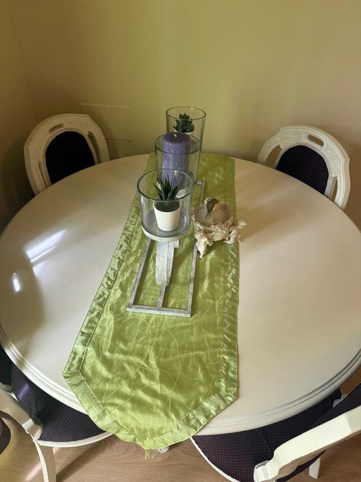 Mesa lacada de branco com quatro cadeiras forradas em tom roxo