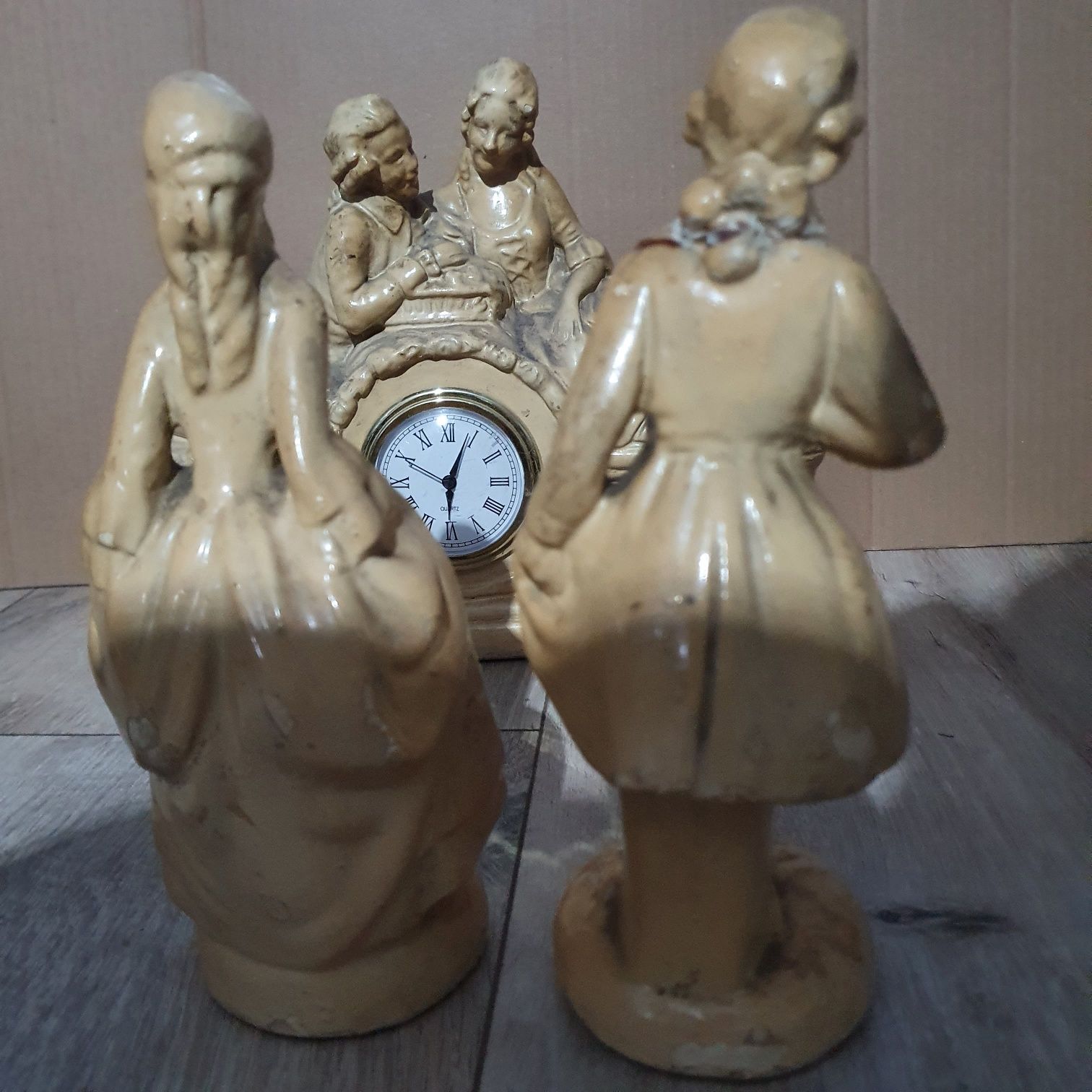 Stary ceramiczny zegar z dwoma figurkami.